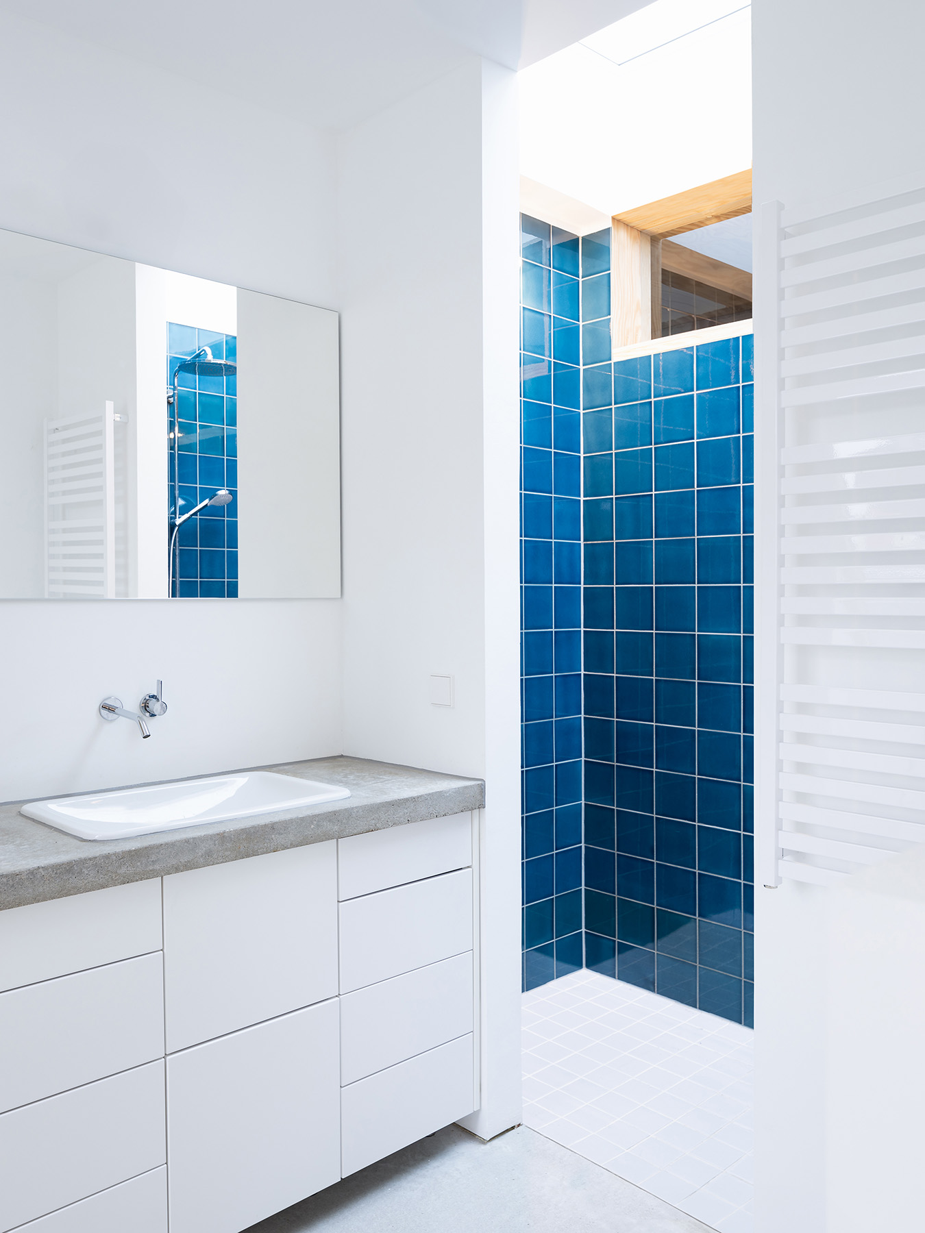 Ausgebauter Dachstuhl mit Einbaumöbeln und Bad mit Oberlicht und blauen Fliesen
