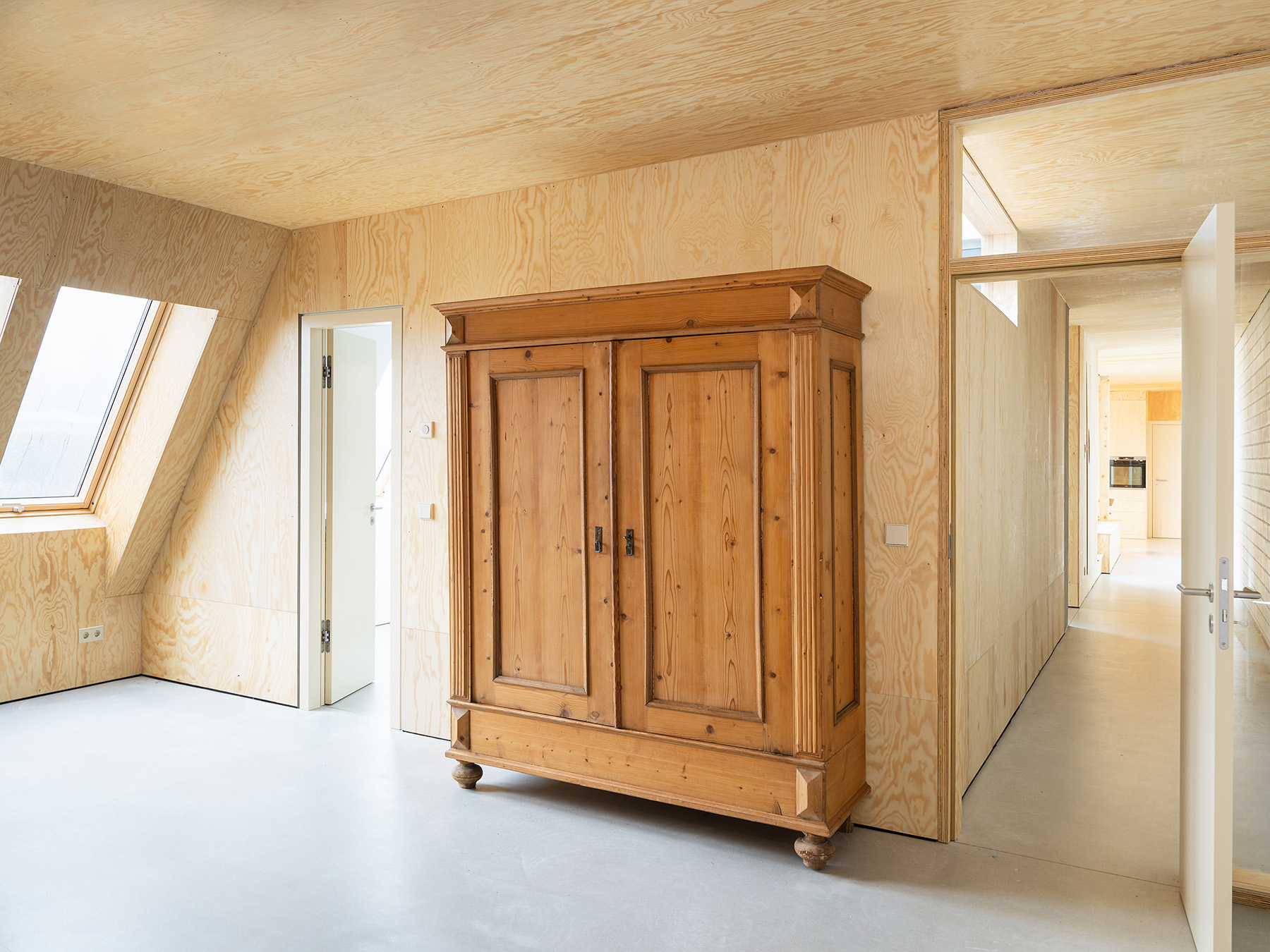 Ausgebauter Dachstuhl mit Einbaumöbeln aus Holz und Sichtestrich für den Boden