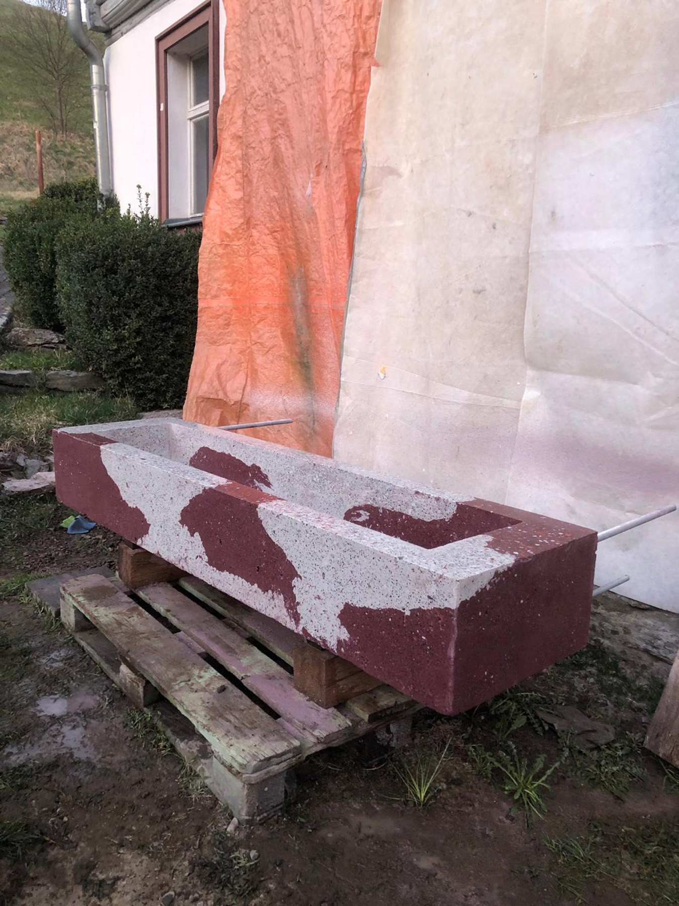 Großes schweres rot weiß geschecktes Waschbecken auf einer Palette