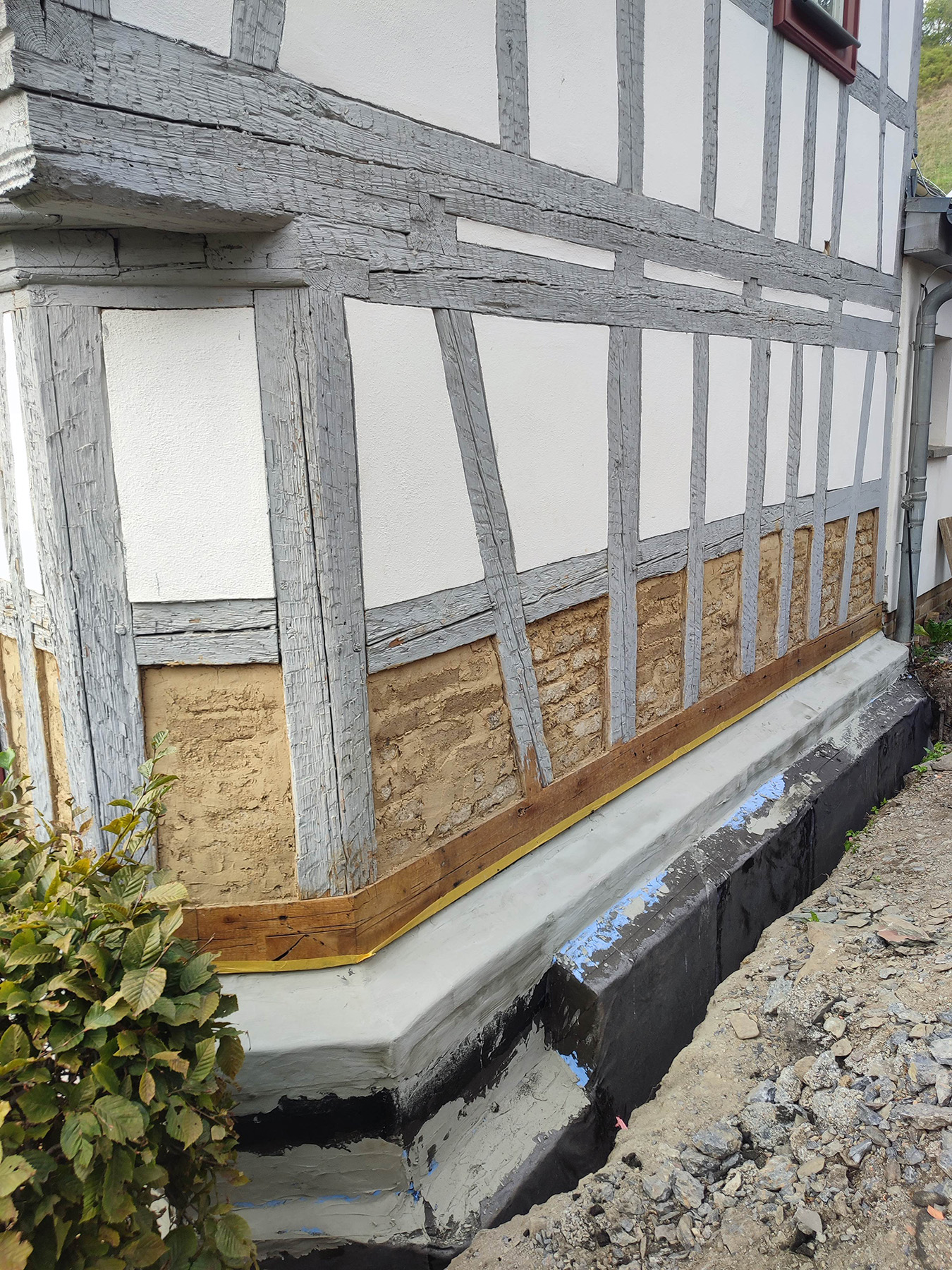 Fachwerkwand mit sanierter Schwelle und neuen Lehmziegeln im Sockelbereich
