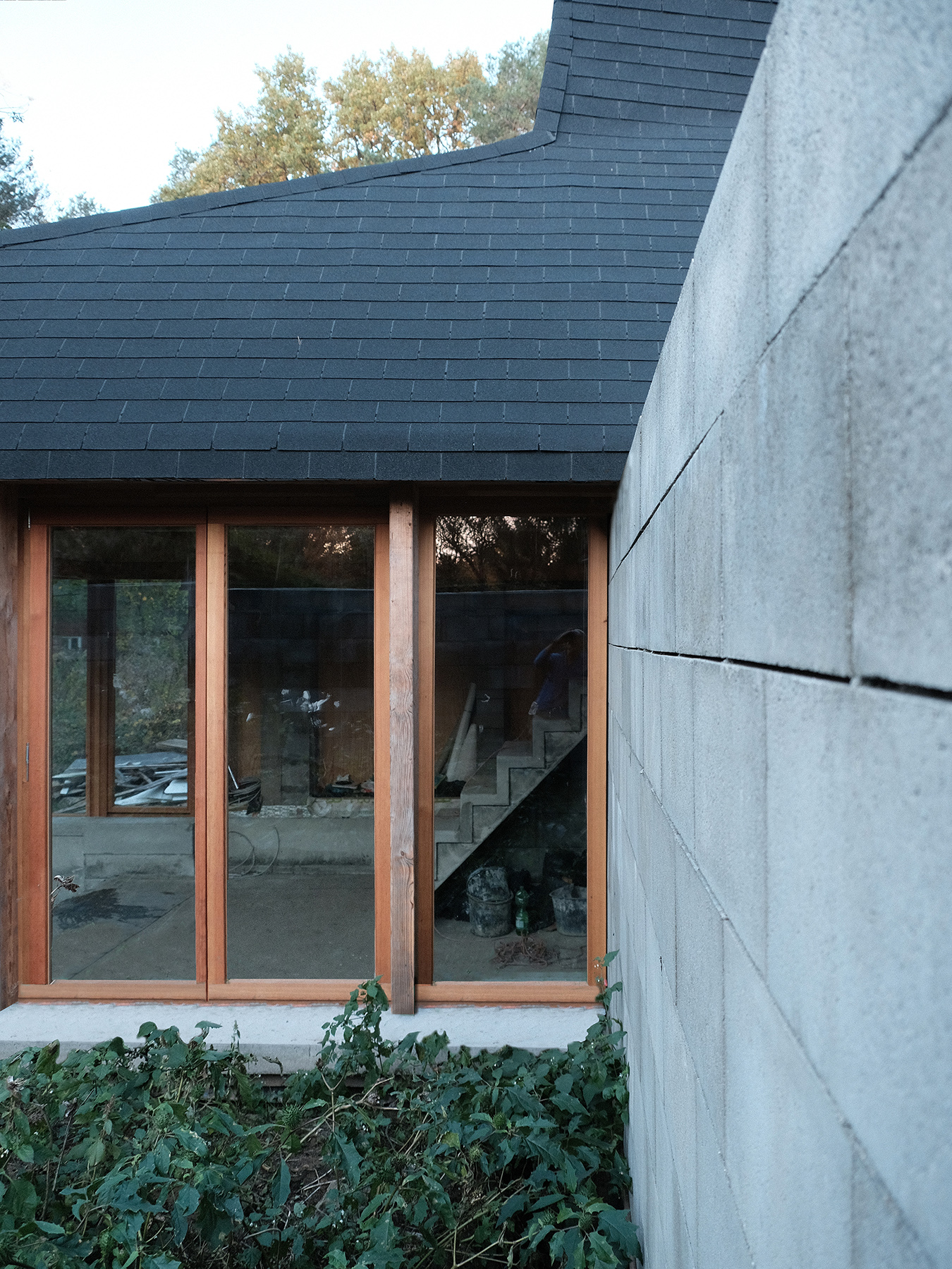 Haus mit Betonsteinmauer, Holzfenstern und Dach mit Bitumenschindeln