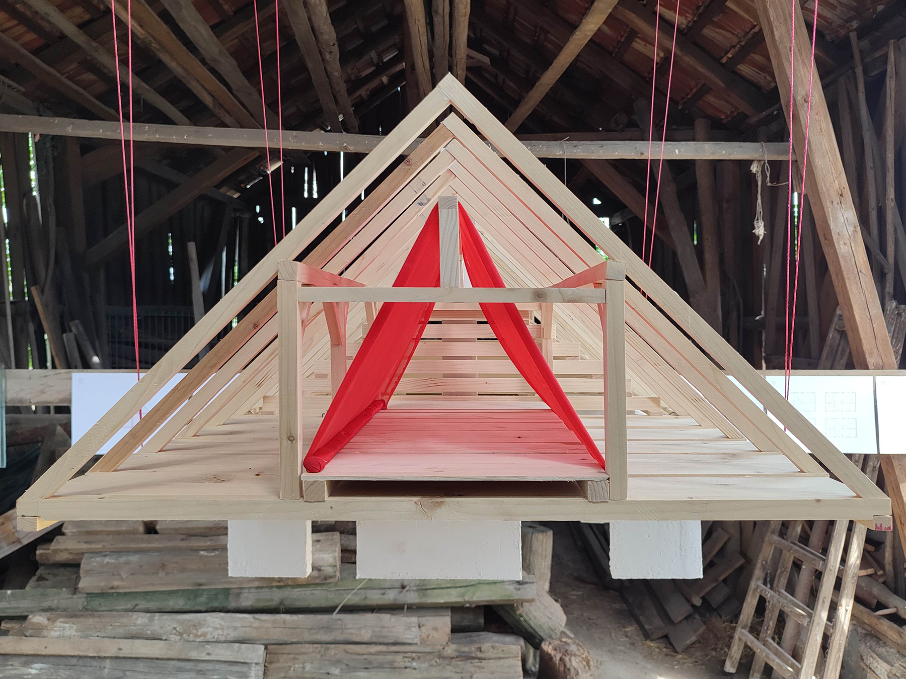 Holzmodell eines Daches das an schnüren in einer alten Scheune hängt